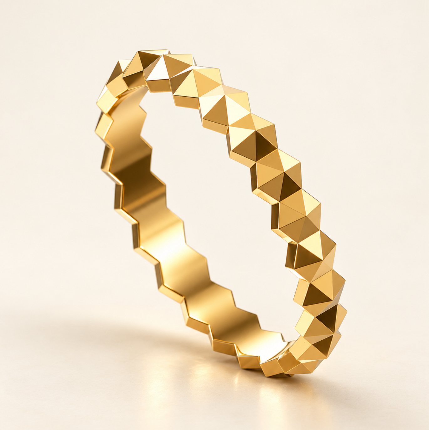 A slim gold band of faceted pyramids standing on an ivory surface